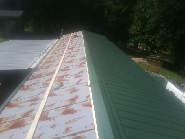 Old rusted panels beside newly installed green metal roofing — Wind Damage Roof Repair by Roofing Brothers in Horseshoe Bend