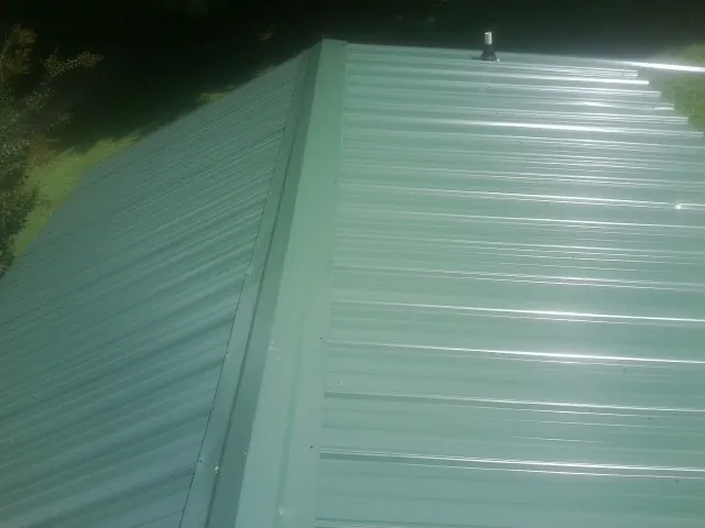 New green metal panels meeting at the ridge of a roof — Flat Roof Repair work by our crew in Horseshoe Bend