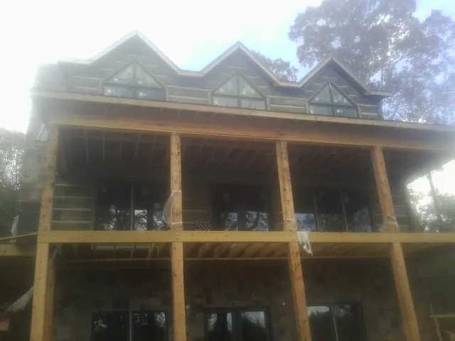 Dormers and porch framing on a large log home under construction — Roof Coating work by our crew in Horseshoe Bend