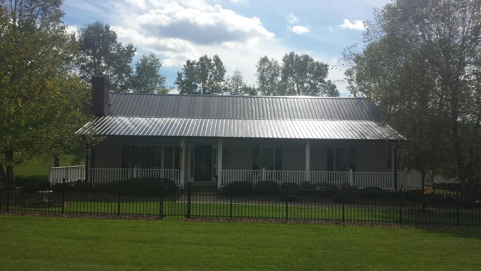 Gray metal roof on a brick ranch with a full width front porch — Gutter Guard Installation work by our crew in Horseshoe Bend