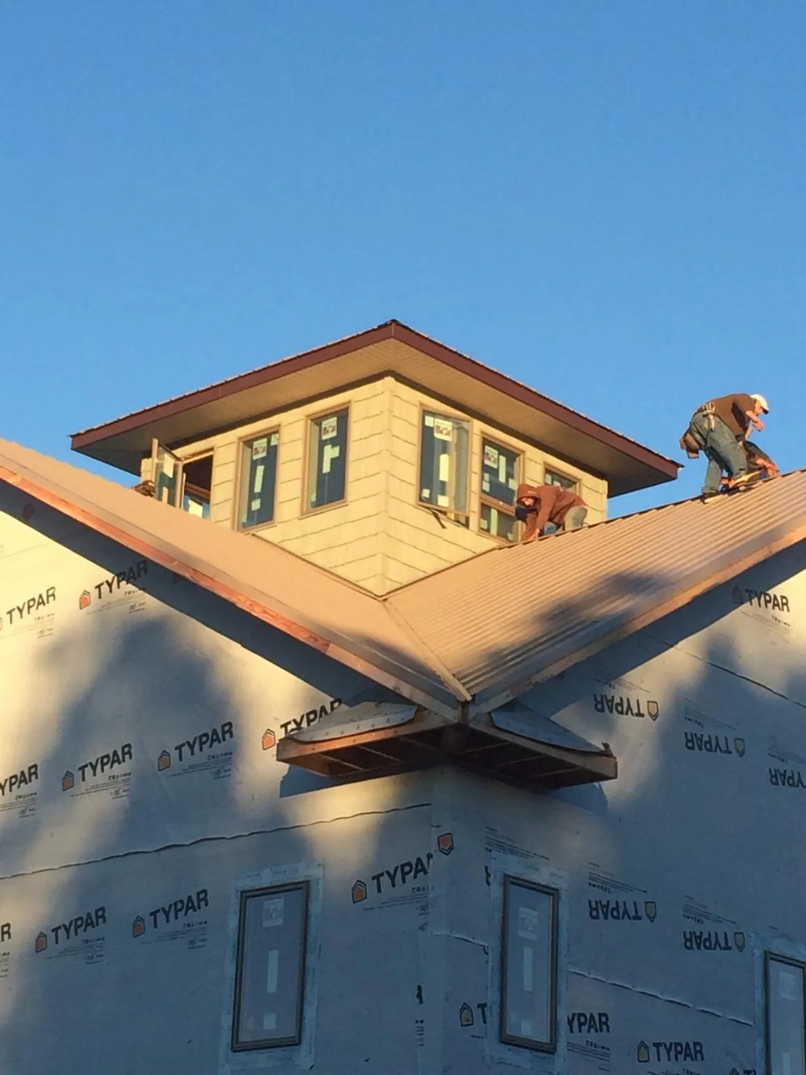 Roofers working around a rooftop cupola on a new metal roof at sunset — Roof Waterproofing in Horseshoe Bend by Roofing Brothers